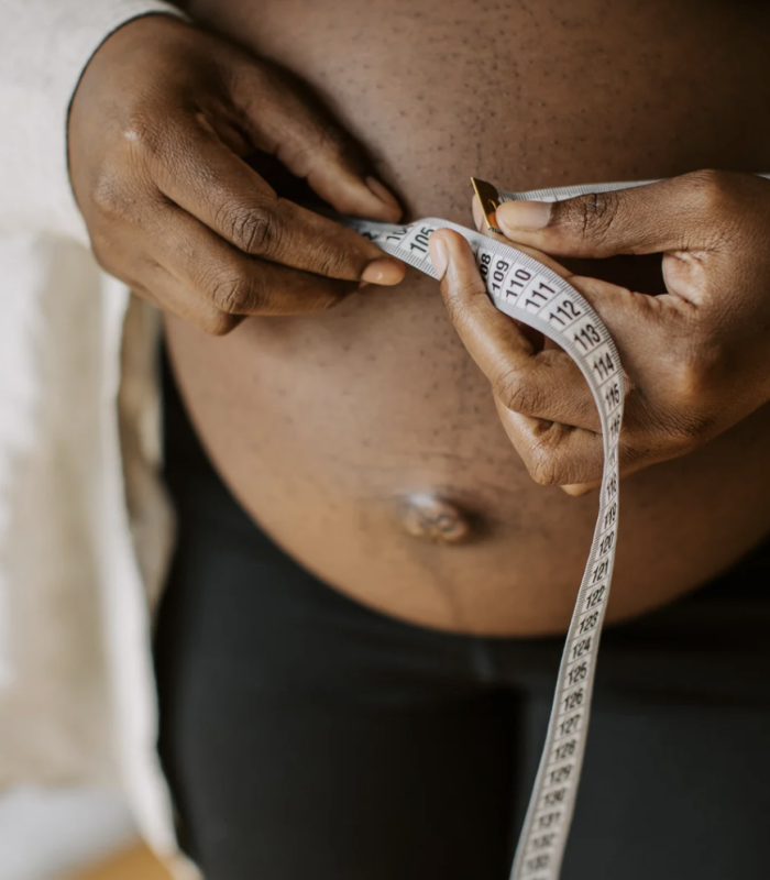 Frau die ihren schwangern Bauch misst